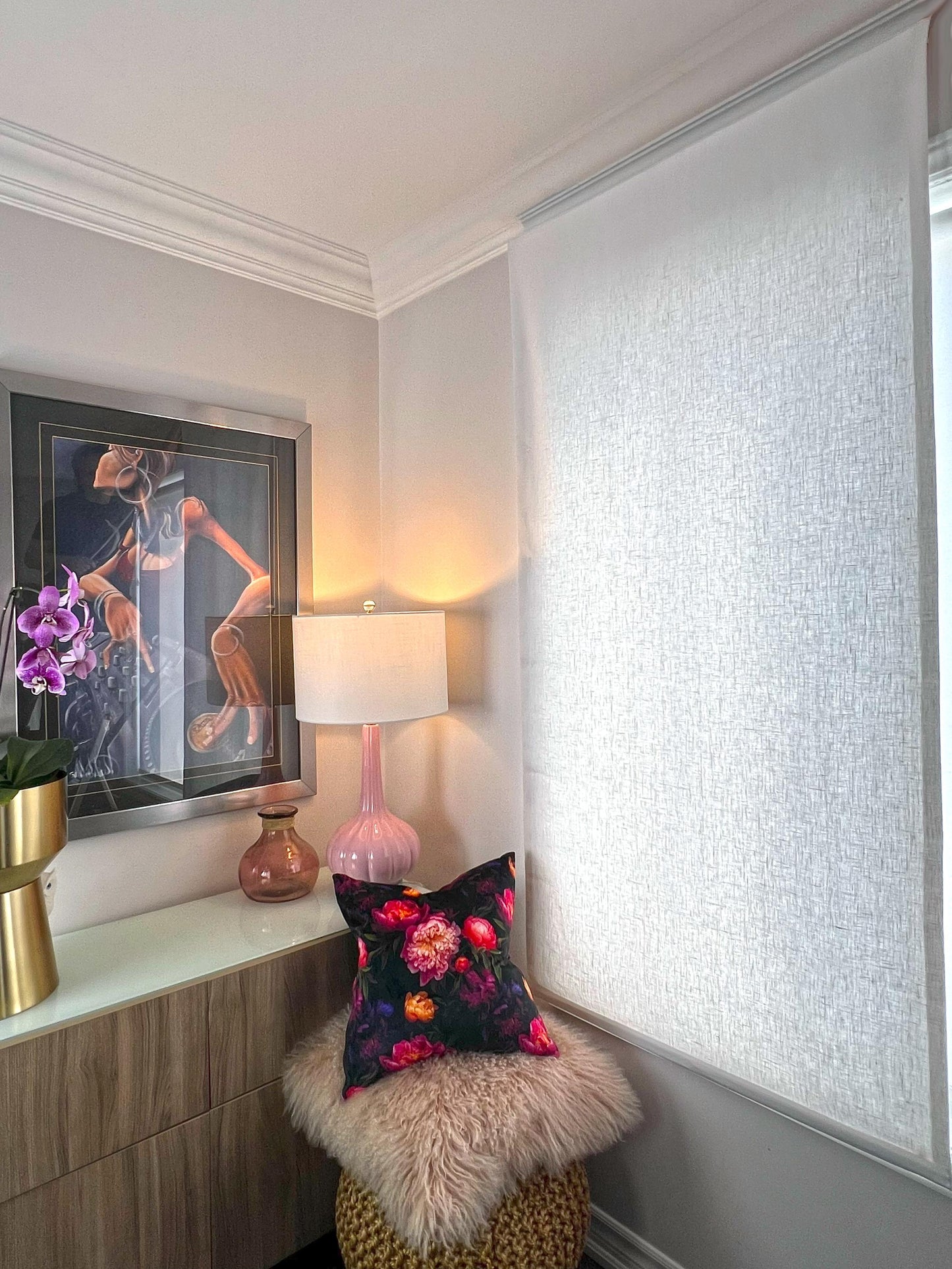White linen relaxed Roman shade lowered, filtering daylight in a bedroom reading corner