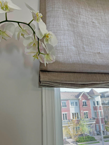 Textured linen Roman shade with an orchid on the sill, daylight through the weave