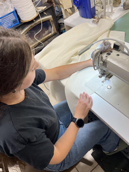 A seamstress in our Toronto workroom sewing a custom linen Roman shade