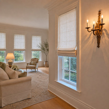 Irish linen relaxed Roman shade beside a brass wall sconce, angled living-room view