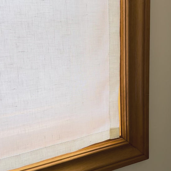 Video: sheer linen cafe curtain fitted inside a wood-framed window, daylight glowing through the open weave