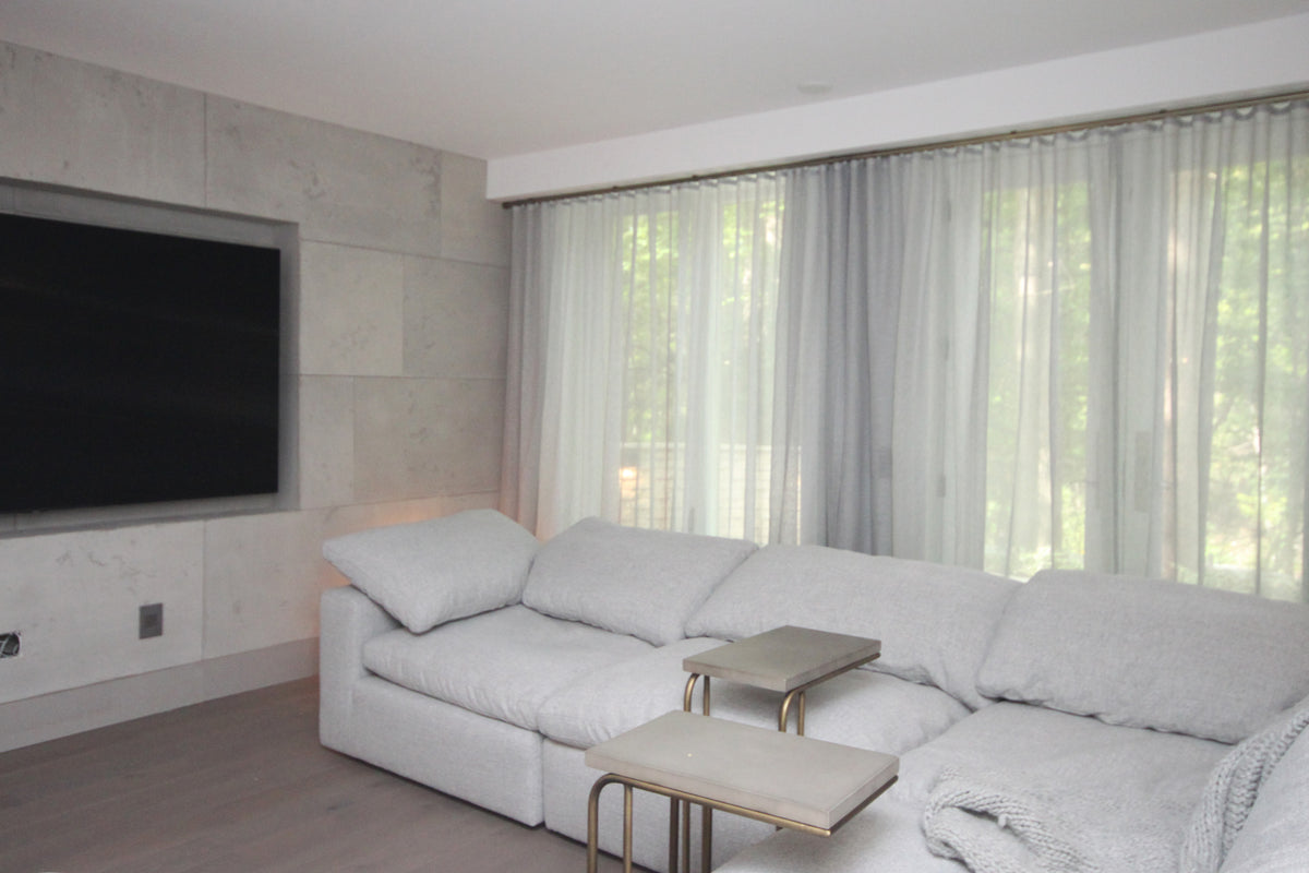Grey Brent sheer ripple fold drapery across a wall of windows in a modern media room with a white sofa
